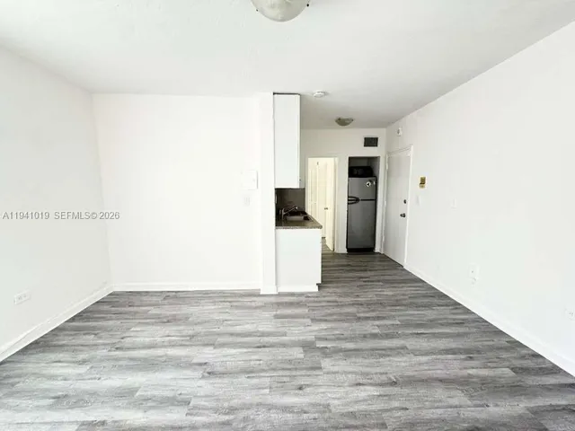 a view of a hallway with wooden floor and cabinet