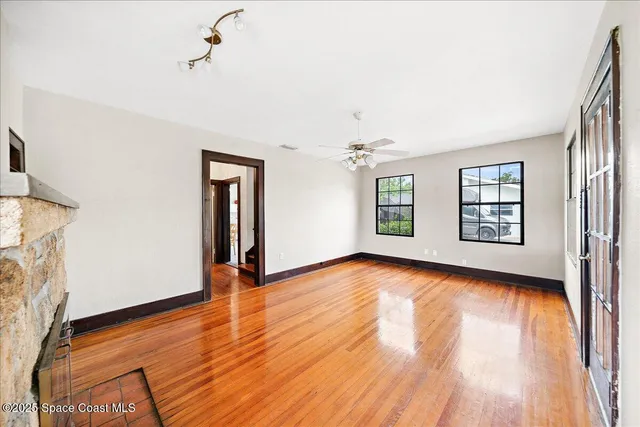 a view of an empty room with window and wooden floor