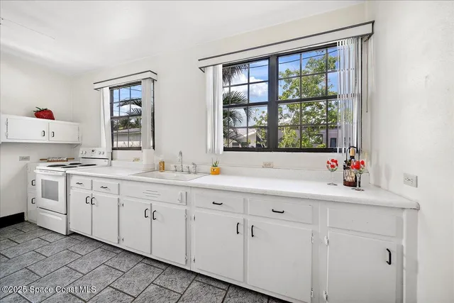 a kitchen with white cabinets and sink