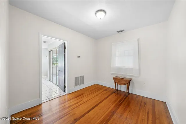 a view of a bedroom with wooden floor and a window