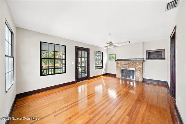 a view of empty room with a fireplace and wooden floor