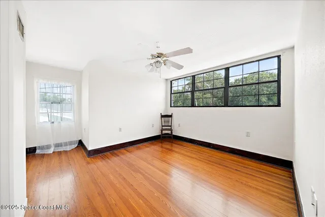 an empty room with wooden floor and windows