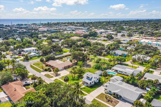 an aerial view of a city with lots of residential buildings ocean and mountain view in back