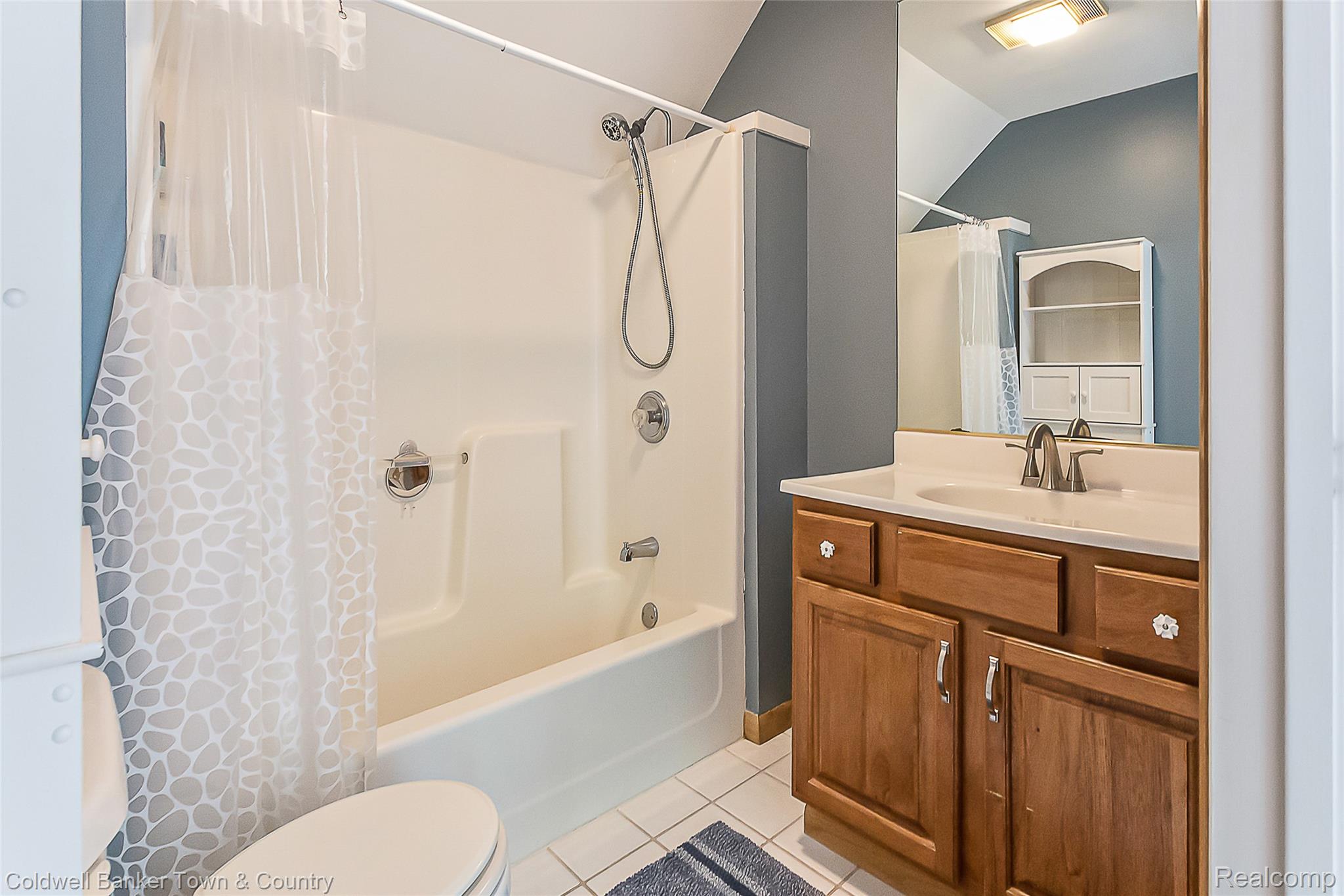 11527 Mcgregor Road Pinckney, MI 48169 - Photo 16 of 26 Full bathroom with light tile patterned flooring, shower / bath combination with curtain, vanity, and vaulted ceiling