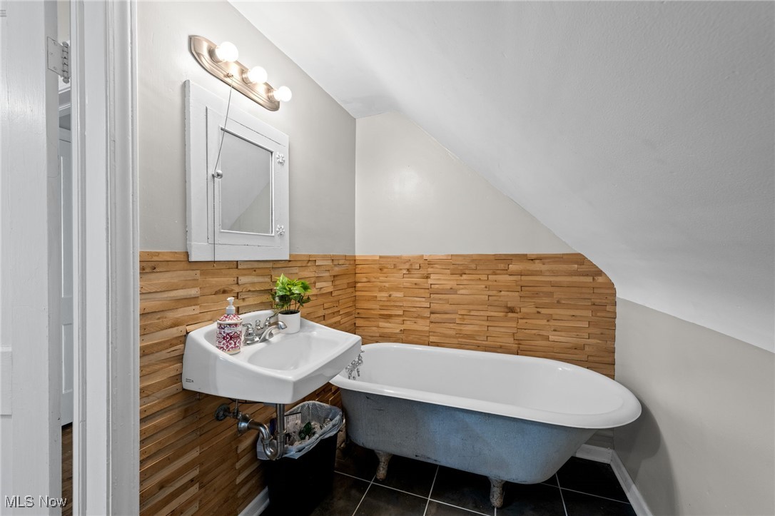 2471 Channing Road Cleveland, OH 44118 - Photo 25 of 33 Bathroom featuring wainscoting, lofted ceiling, tile patterned floors, a soaking tub, and a sink