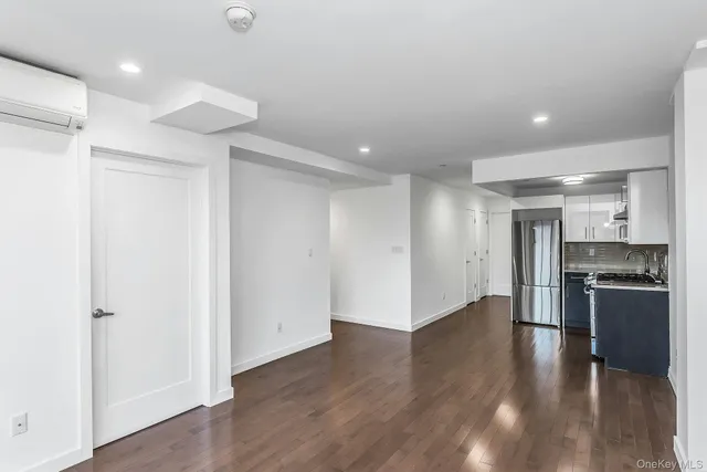 an empty room with wooden floor and a kitchen