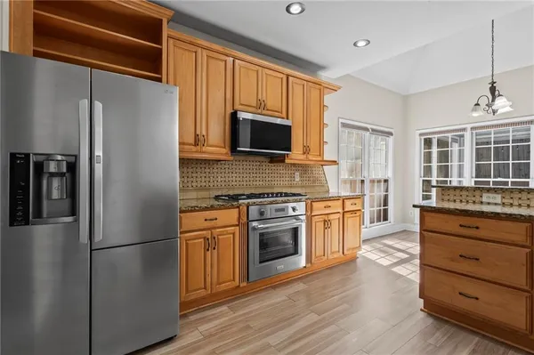 a kitchen with granite countertop stainless steel appliances a refrigerator stove top oven and sink