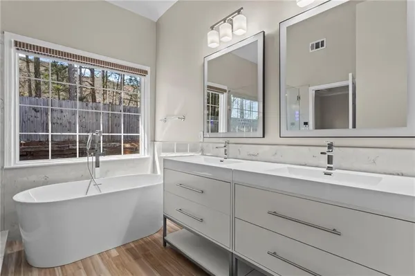 a bathroom with a tub a sink and a large mirror