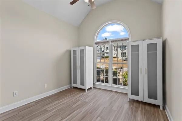 an empty room with wooden floor cabinet and windows