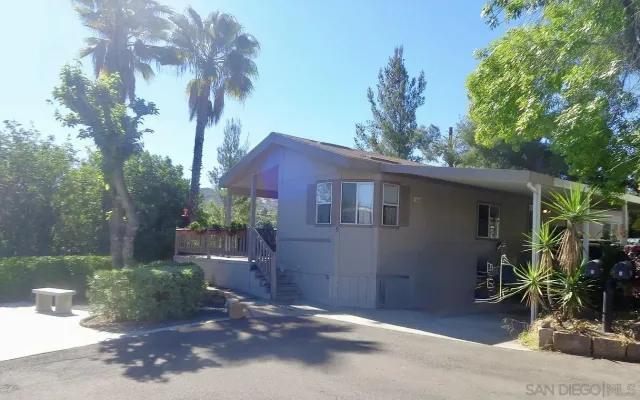 a backyard of a house with table and chairs under an umbrella