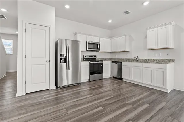 a kitchen with stainless steel appliances granite countertop a refrigerator and a stove top oven