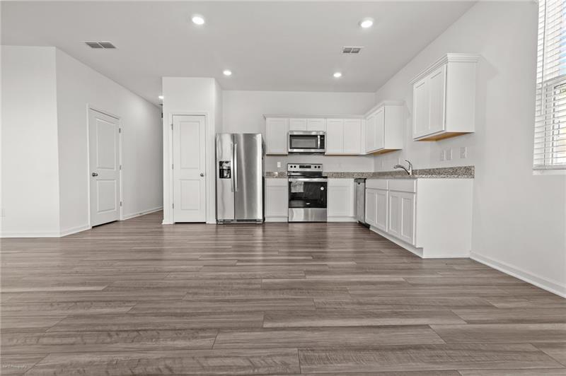 103 Rydal Way Winder, GA 30680 - Photo 12 of 31 a kitchen with stainless steel appliances granite countertop a stove top oven a sink dishwasher and a refrigerator with wooden floor
