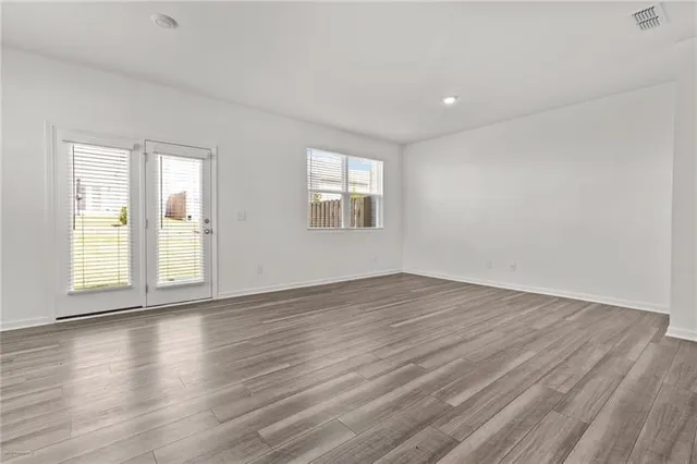 an empty room with wooden floor and windows