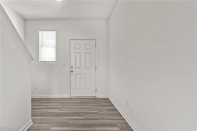a view of hallway with window and wooden floor
