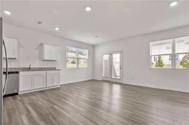 a view of an empty room with window and wooden floor