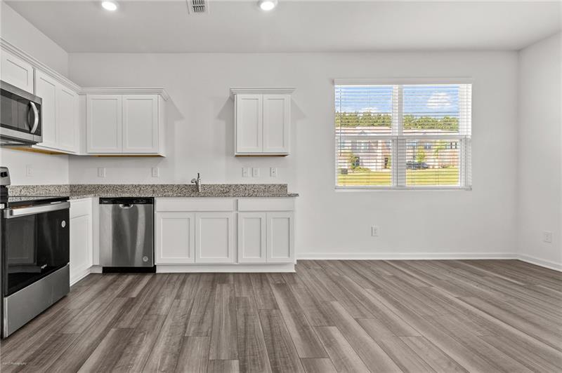 103 Rydal Way Winder, GA 30680 - Photo 9 of 31 a kitchen with granite countertop wooden floors stainless steel appliances and sink
