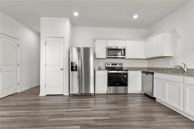 a kitchen with granite countertop a refrigerator and a stove top oven