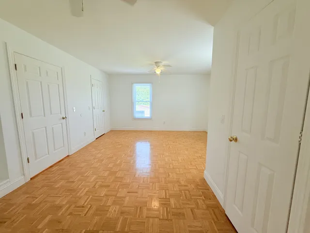 an empty room with a chandelier fan and windows