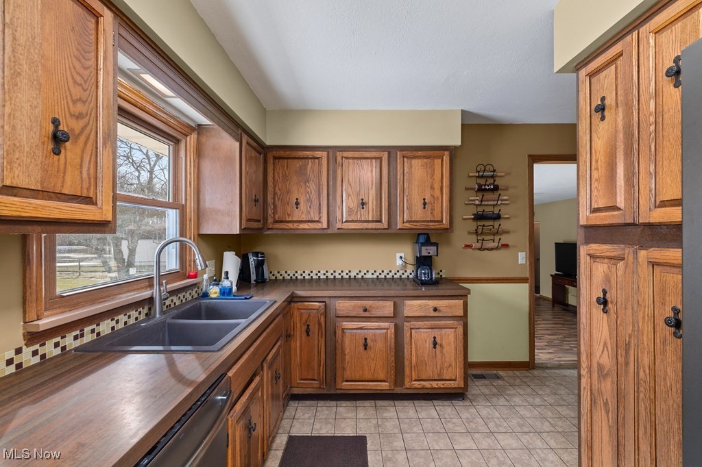 8238 Ruff Road West Salem, OH 44287 - Photo 10 of 27 Kitchen featuring brown cabinetry, dark countertops, a sink, and visible vents