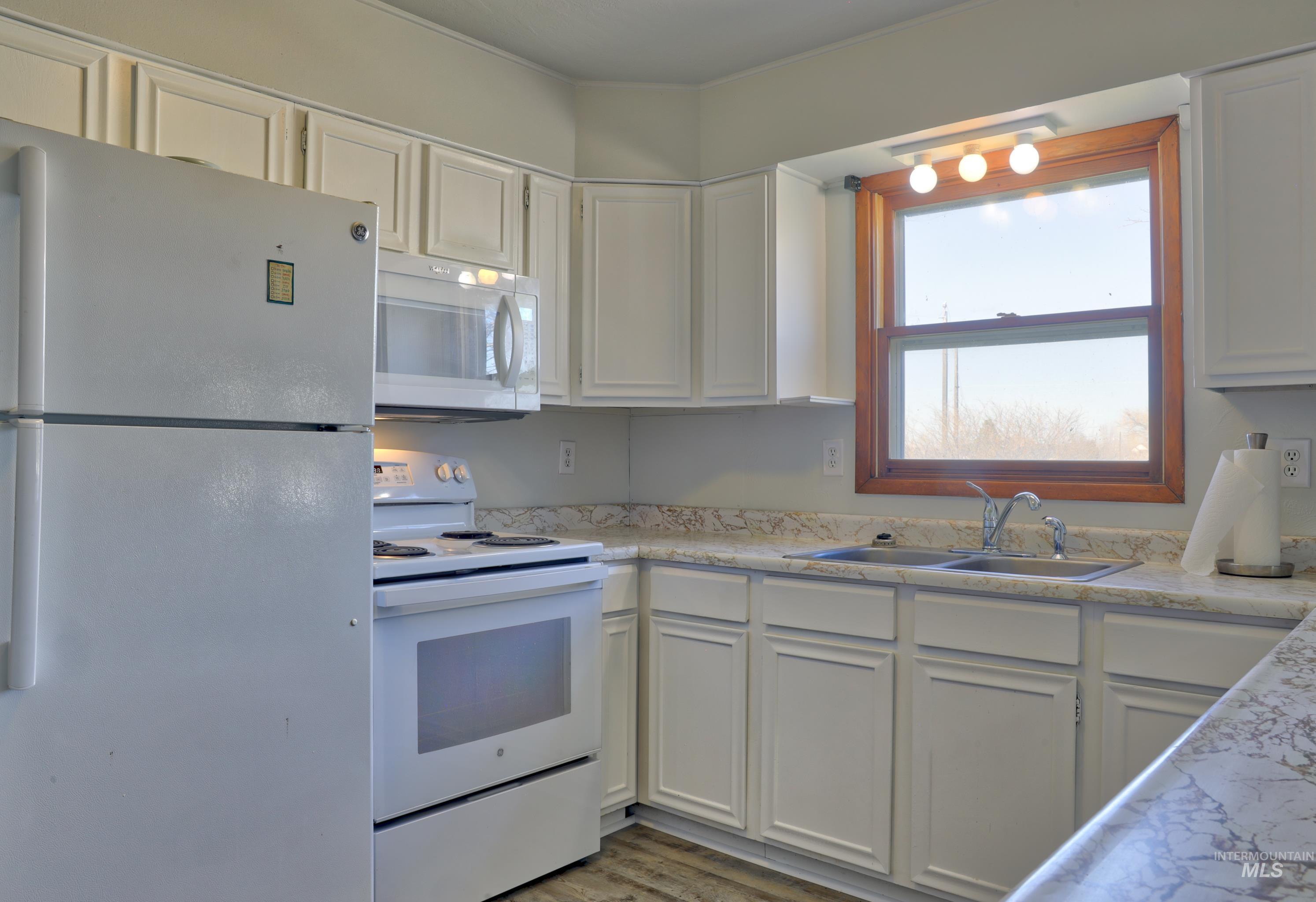 8027 Chuckar Lane Boise, ID 83709 - Photo 8 of 19 Kitchen featuring white appliances, white cabinets, light countertops, and light wood-style flooring