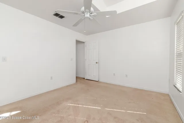 an empty room with a window and a ceiling fan