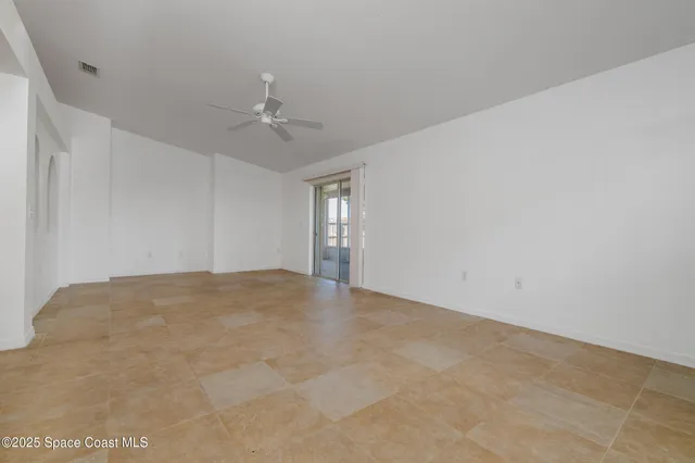 an empty room with chandelier fan and ceiling fan