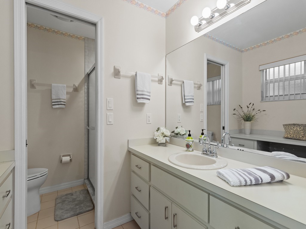 765 Date Palm Road Vero Beach, FL 32963 - Photo 19 of 36 a bathroom with a granite countertop sink a toilet and a mirror