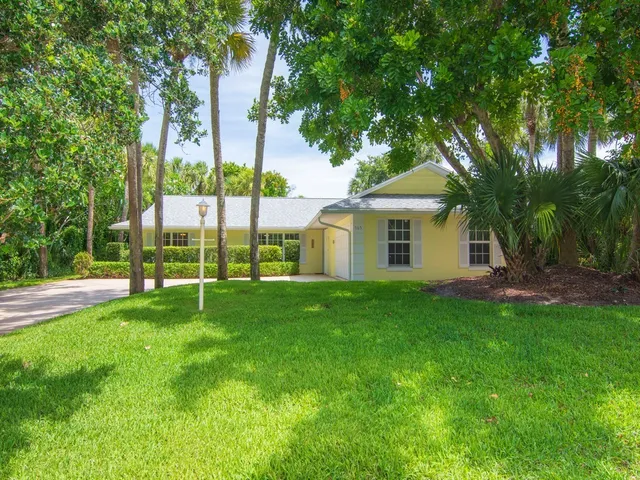 a view of a house with a yard and palm trees