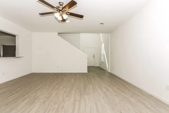 a view of a room with wooden floor and a ceiling fan