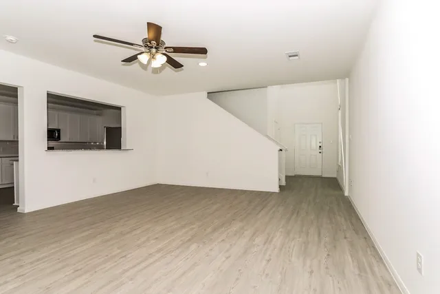 a view of a livingroom with wooden floor and a ceiling fan