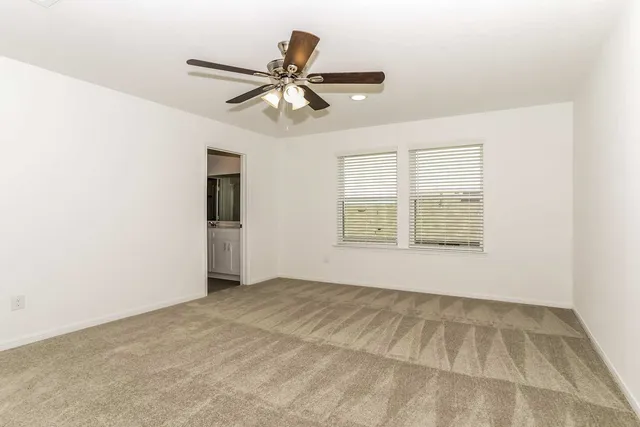 an empty room with a ceiling fan and a window
