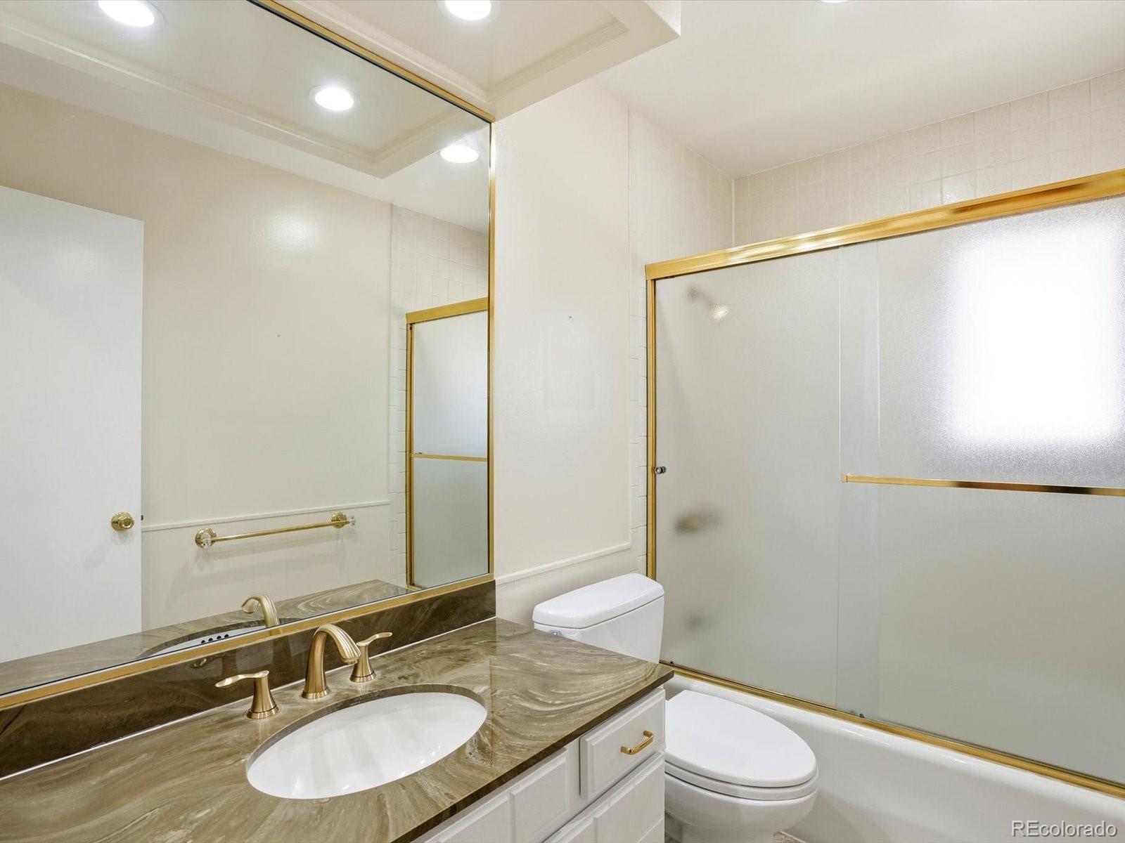 3330 South Oneida Way Denver, CO 80224 - Photo 24 of 36 a bathroom with a granite countertop sink toilet a mirror and shower