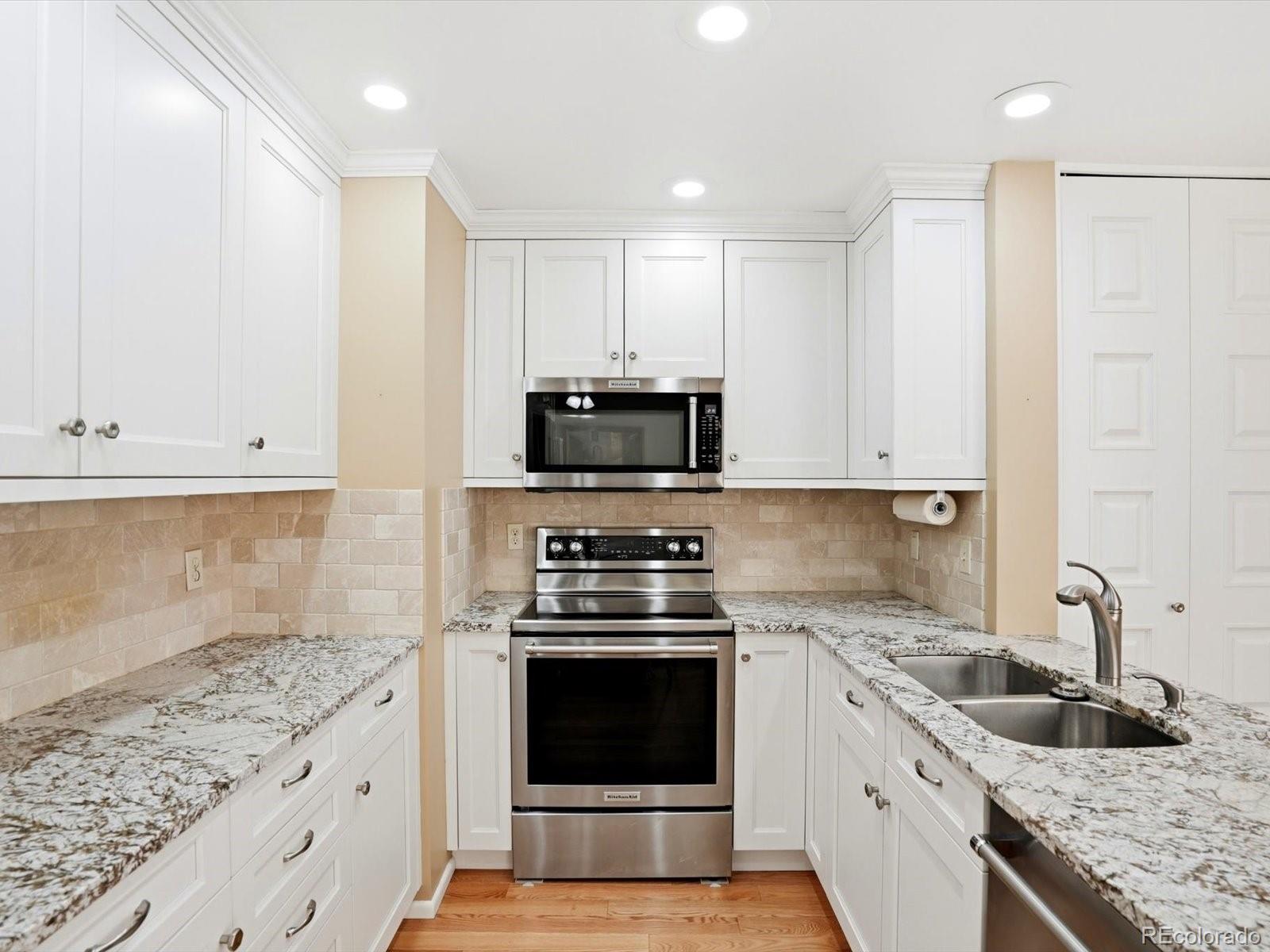 3330 South Oneida Way Denver, CO 80224 - Photo 8 of 36 a kitchen with granite countertop a stove sink and cabinets