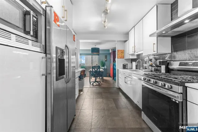 a kitchen with stainless steel appliances granite countertop a refrigerator a stove and a refrigerator