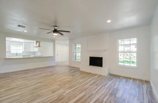 a view of an empty room with a window and wooden floor