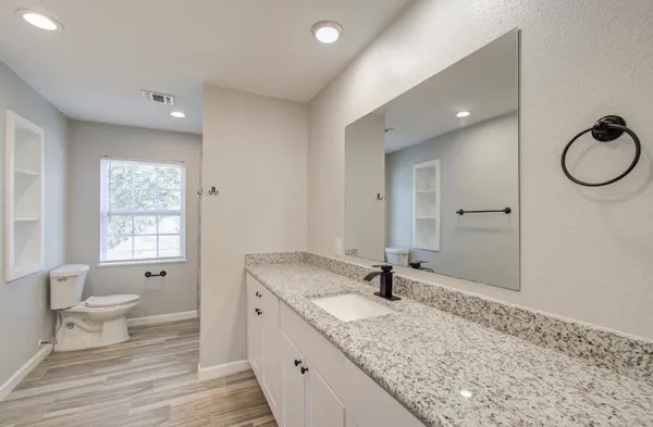a bathroom with a granite countertop sink mirror and a toilet