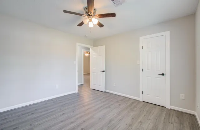 an empty room with wooden floor and ceiling fan