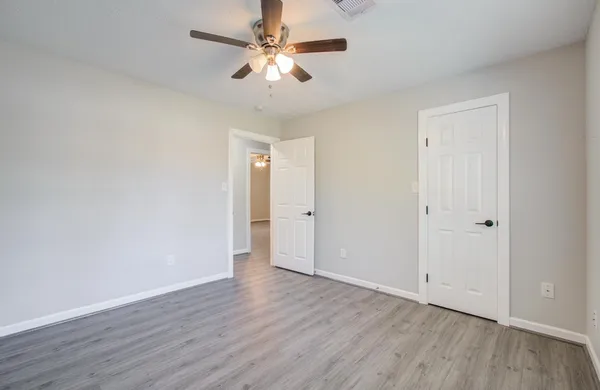 an empty room with wooden floor and ceiling fan