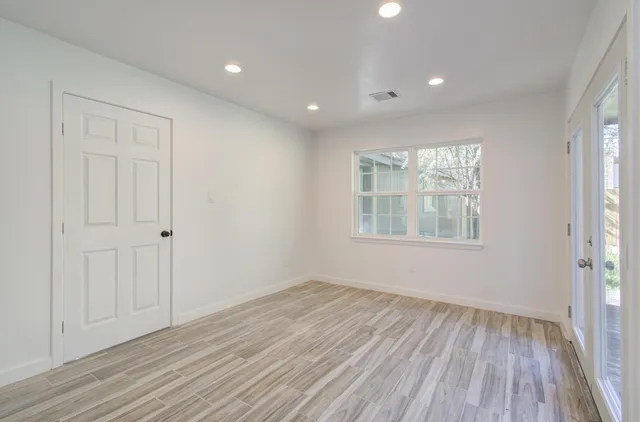 a view of an empty room with wooden floor and a window