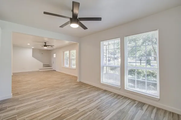 a view of an empty room with wooden floor and a window