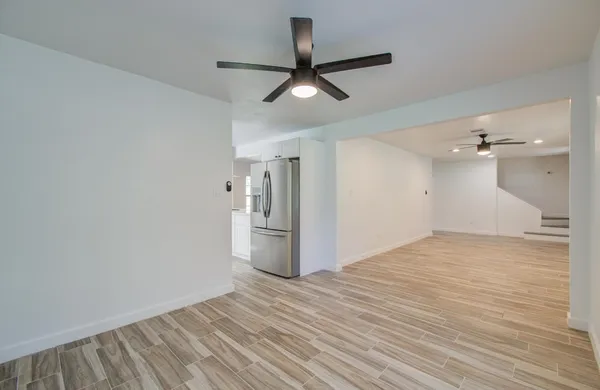 a view of empty room with wooden floor and ceiling fan