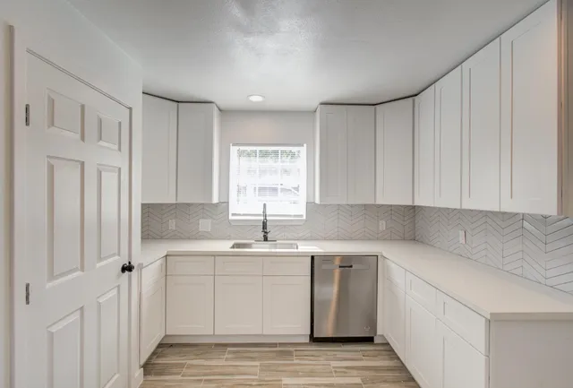 a kitchen with a sink cabinets appliances and a window