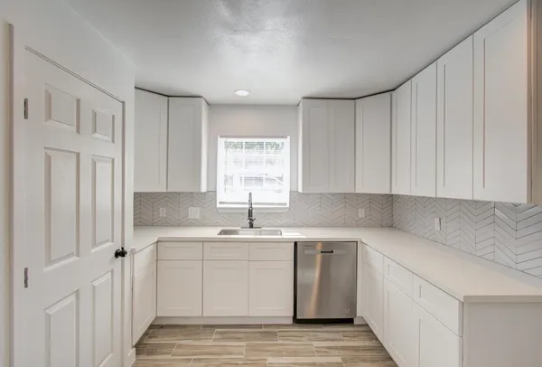 a kitchen with a sink cabinets appliances and a window