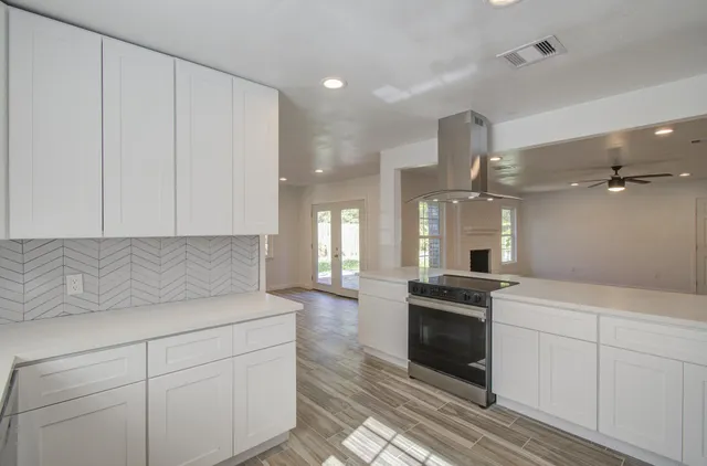 a kitchen with granite countertop white cabinets and stainless steel appliances