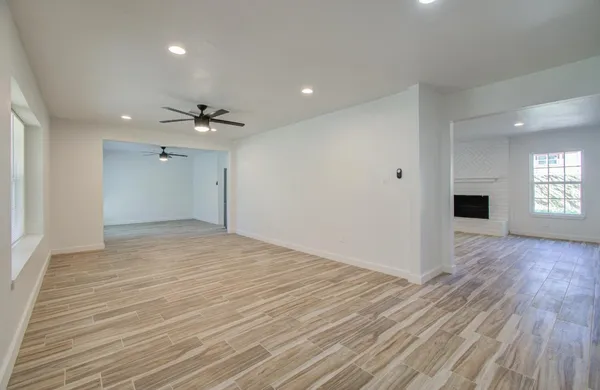 a view of empty room with wooden floor and fan