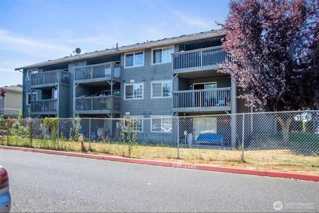 a view of a house with a small yard and large trees