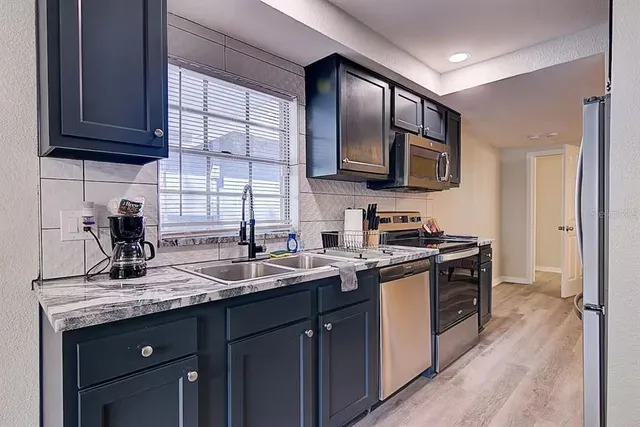 a kitchen with stainless steel appliances granite countertop a sink stove and refrigerator
