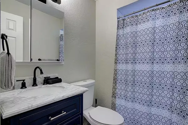 a bathroom with a granite countertop toilet sink and mirror