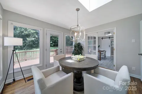 a view of a livingroom and dining room with furniture wooden floor a chandelier