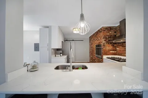 a view of a kitchen with granite countertop a sink stainless steel appliances and a chandelier